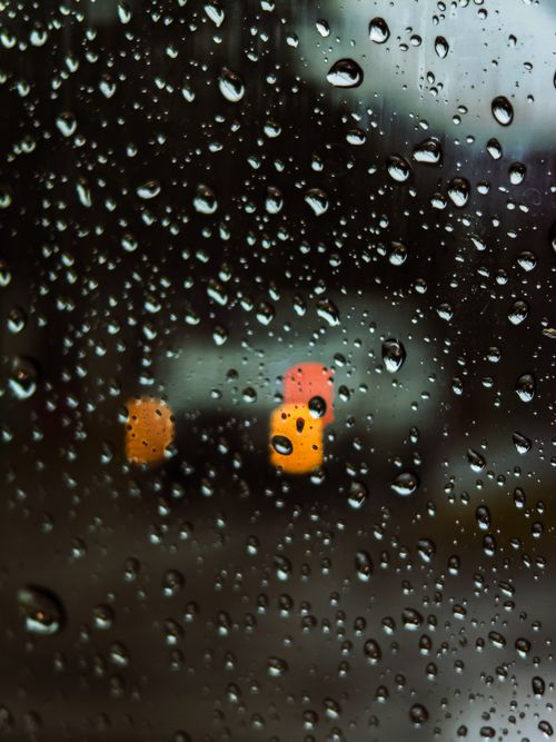 Free Blurred city lights through a rain-soaked window in Jakarta Utara, creating a moody atmosphere. Stock Photo