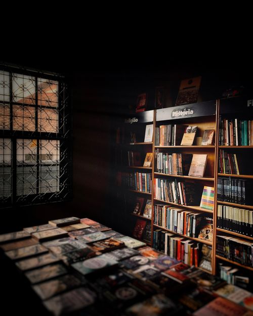 Free A warm, inviting bookstore corner with bookshelves and a softly lit table display. Stock Photo
