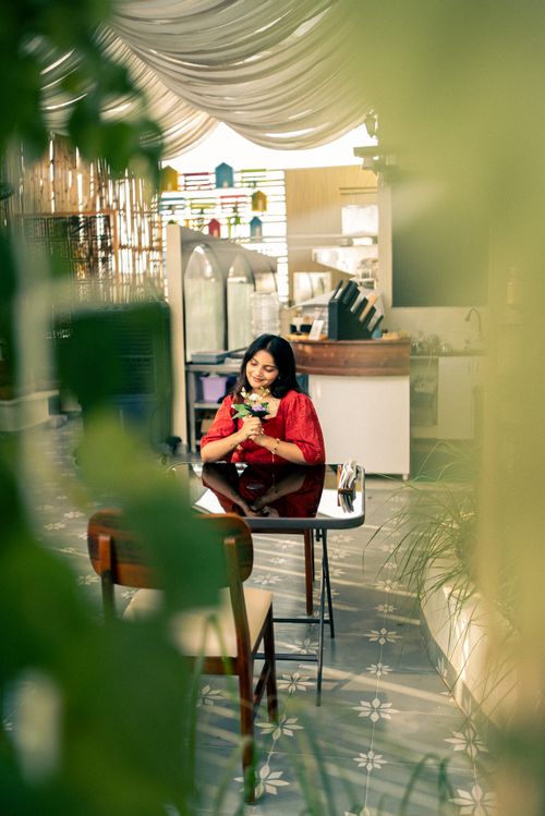Free A woman in a red dress enjoys a coffee in an urban cafe with modern decor. Stock Photo