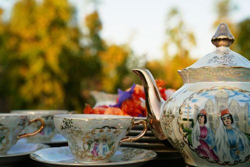 Free An elegant tea set with decorative teapot and cups in a sunlit outdoor setting with trees. Stock Photo