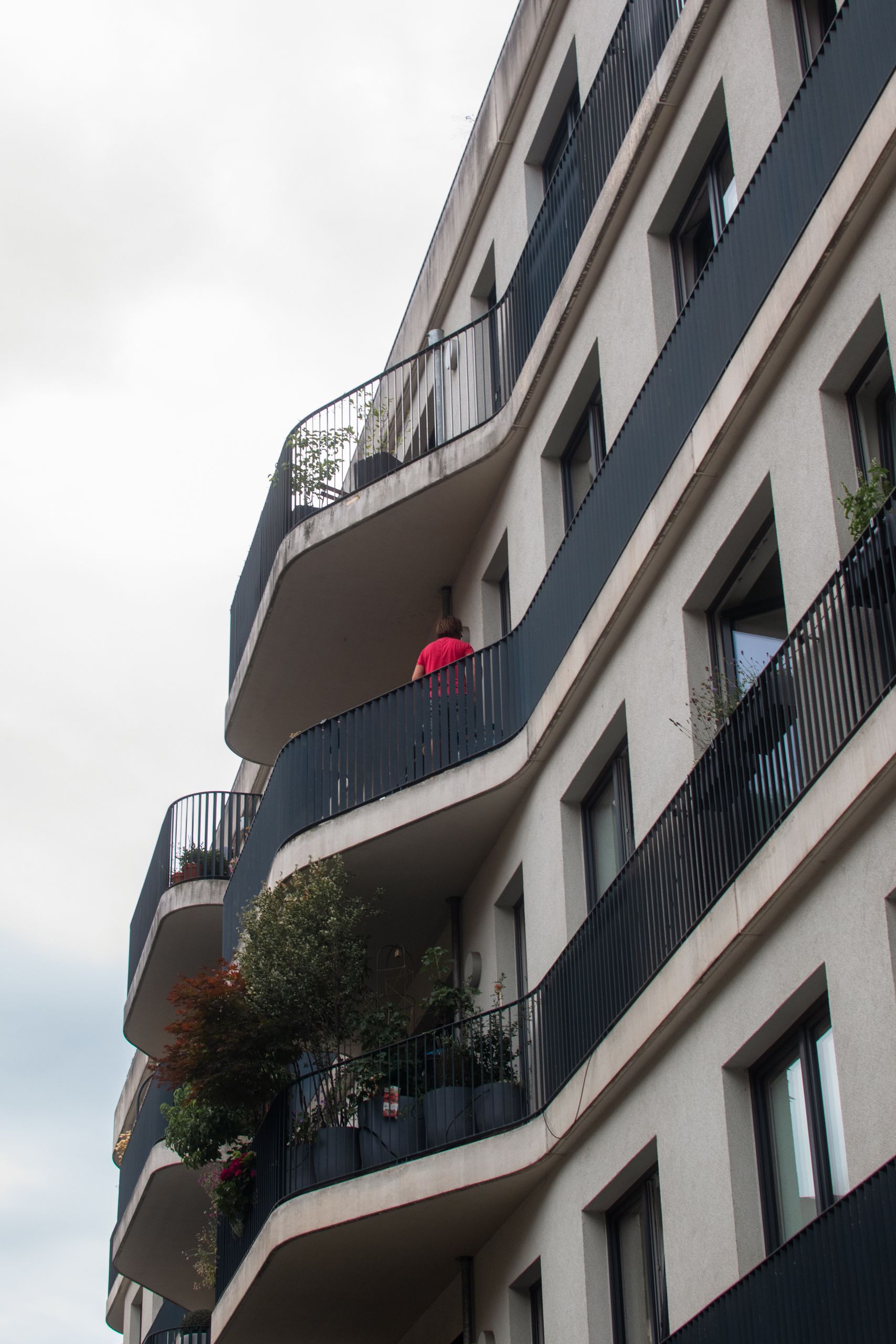 Contemporary residential building with sleek balconies and a person in view.