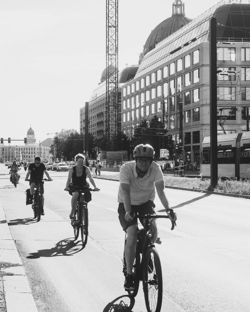 Free Black and white photo of cyclists on a city street with modern architecture. Stock Photo