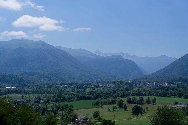 Village pyrénéen en panorama, niché dans une vallée sous des sommets striés de nuages