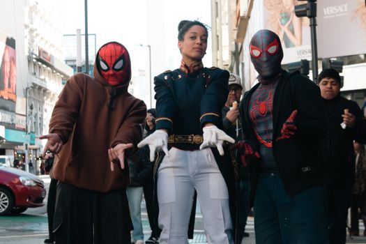 Three people in costume posing on a busy city street.