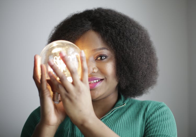 Woman In Green Shirt Holding Lightbulb