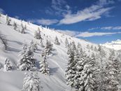 在蔚蓝的天空下，滑雪者可以欣赏到白雪皑皑的高山斜坡，景色令人惊叹