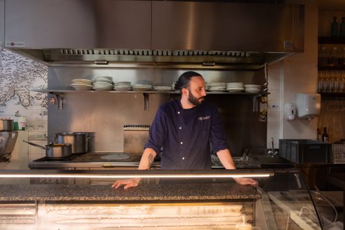 Free A male chef stands leaning on a counter in a professional restaurant kitchen. Stock Photo