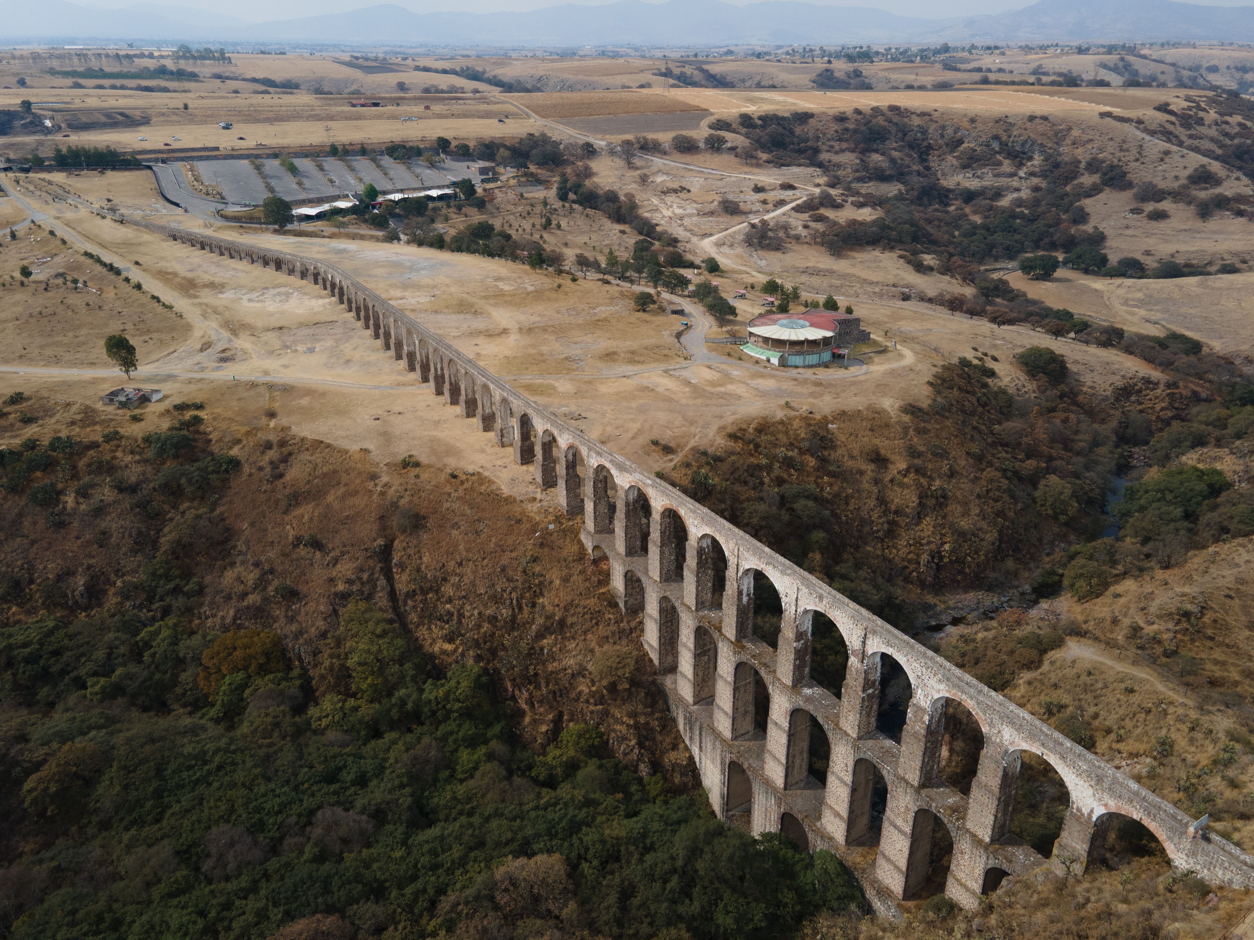 Aerial photograph of the historic Arcos del Sitio aqueduct in Tepotzotlán, Mexico, amidst dry landscape.