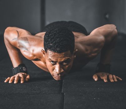 Focused man doing a push-up workout in a gym, showcasing strength and determination.