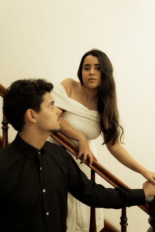 Free A sophisticated couple poses gracefully on a staircase in a warm, intimate setting. Stock Photo
