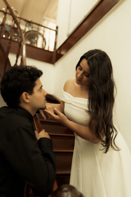 Free Couple in stylish attire sharing an intimate moment on a staircase indoors. Stock Photo