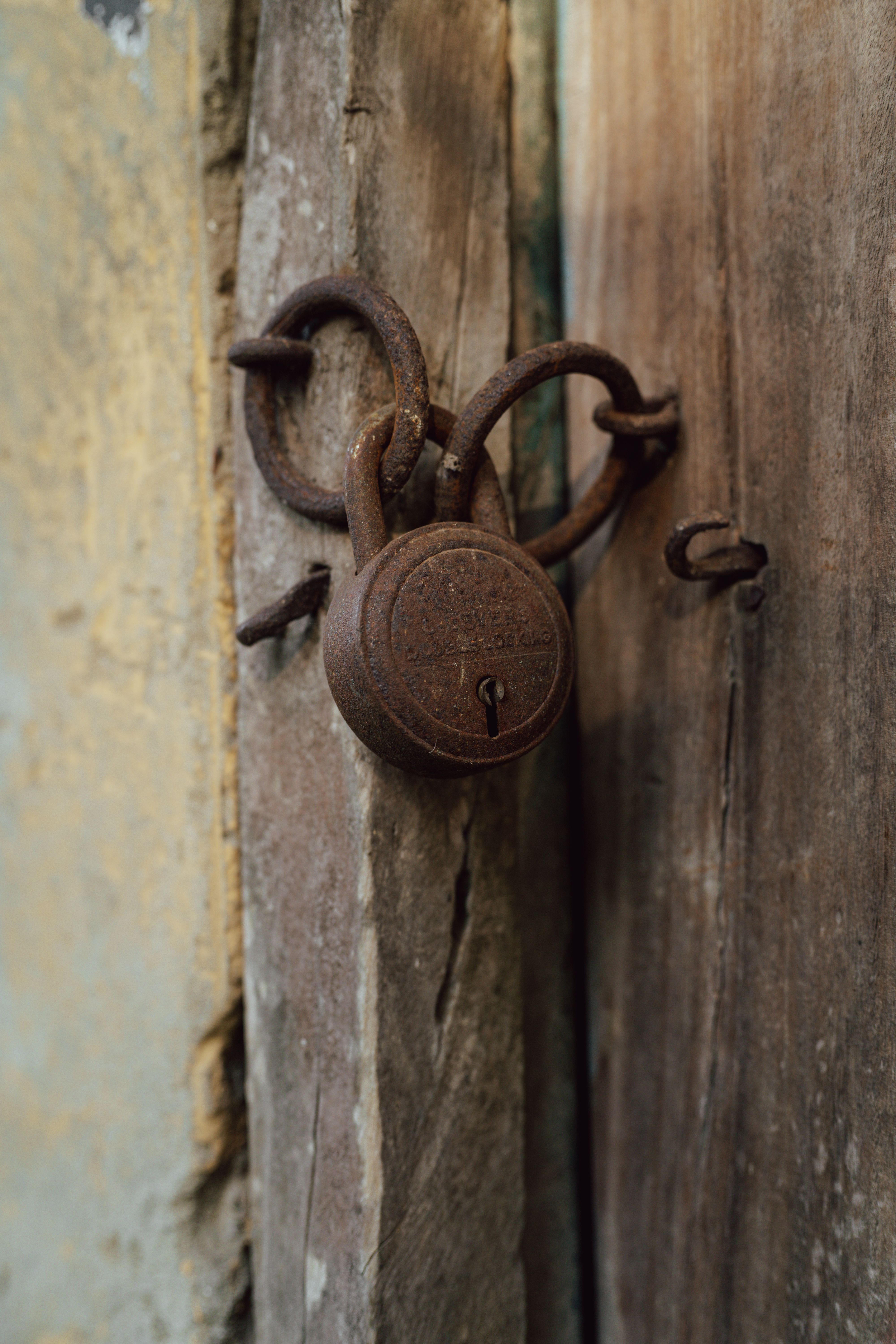 Fotomural Primer plano de un viejo candado oxidado en una puerta de madera desgastada, que simboliza seguridad y tradición.