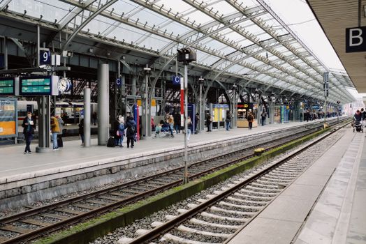 Busy modern train station platform with passengers waiting and boarding trains.