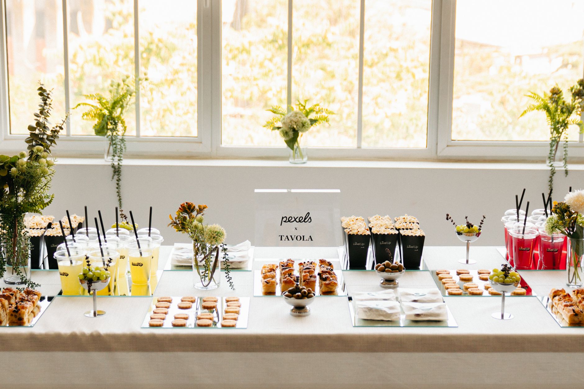 Beautifully arranged buffet table with snacks, drinks, and floral decorations at an indoor event.