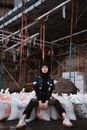 一位穿着街头服饰的时尚女子自信地在有脚手架的工地上摆姿势