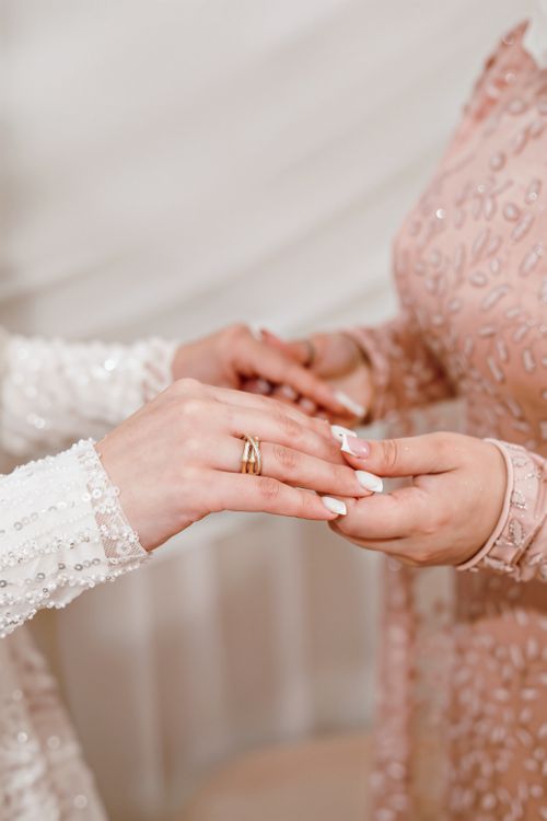 Free Close-up of a bride and groom exchanging rings with intricate dress details. Stock Photo