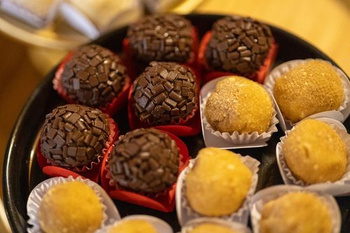 Free A close-up of assorted brigadeiros and beijinhos on a black tray, highlighting their texture and color. Stock Photo