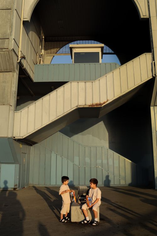 Free Two children playing under an urban staircase, creating dynamic shadows. Stock Photo