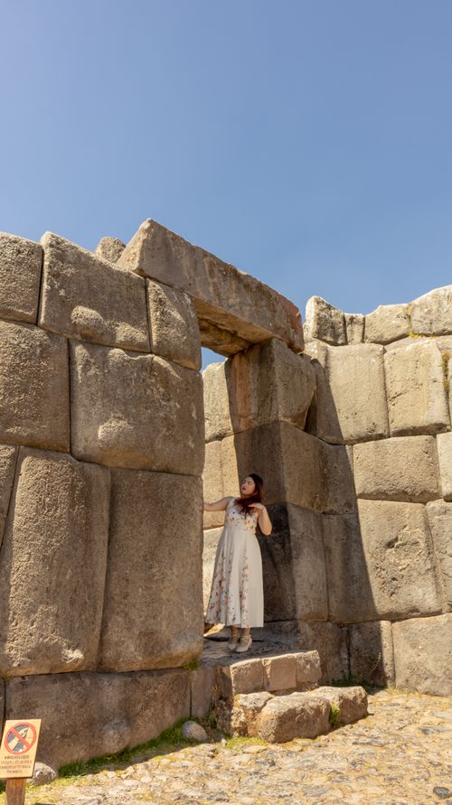 Free Woman in white dress exploring ancient stone ruins under a clear sky. Stock Photo