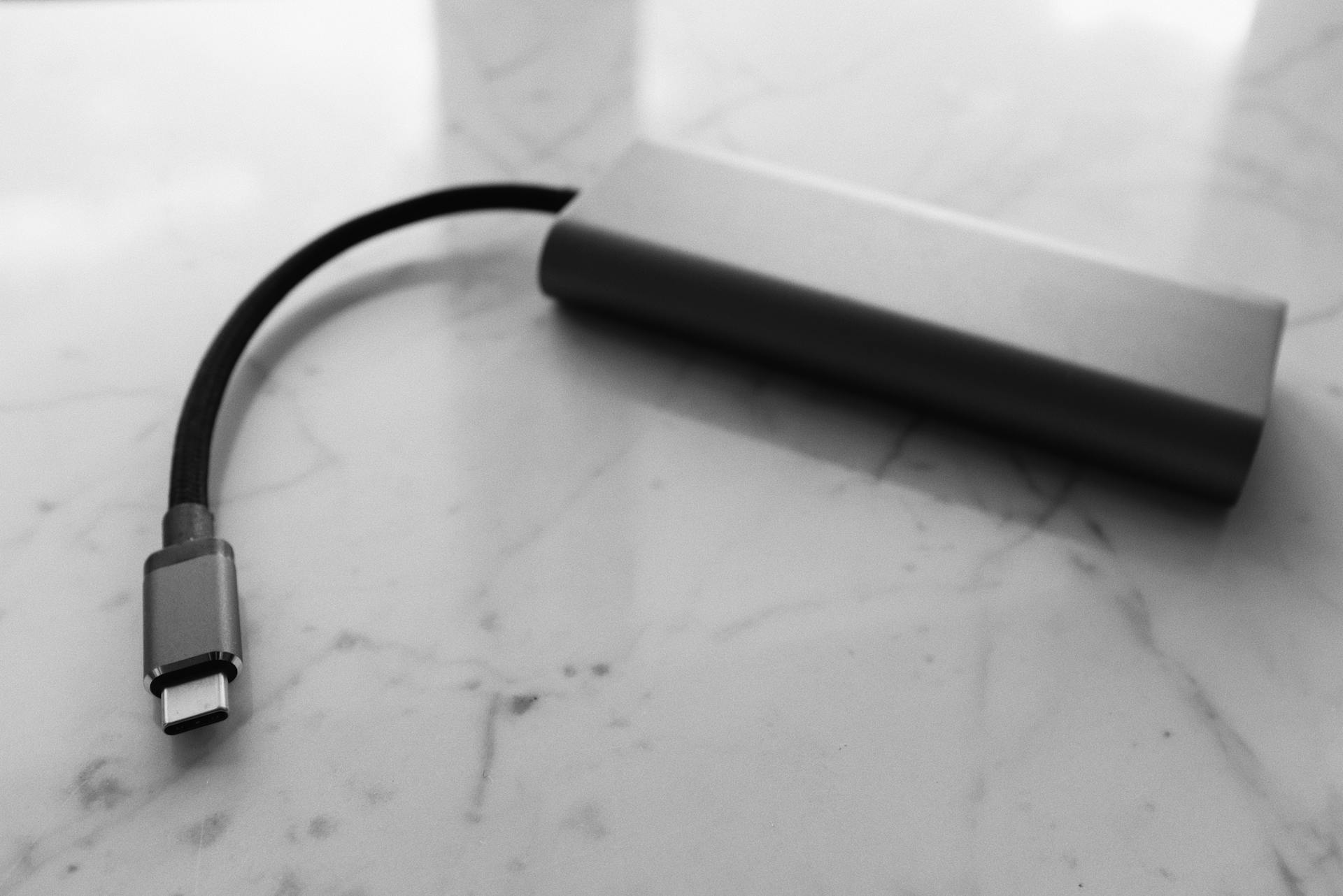 A minimalist black and white image of a USB-C power bank on a marble surface.