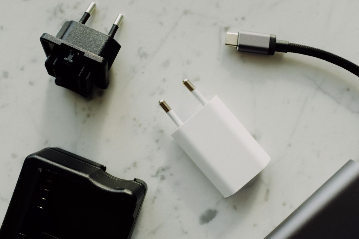 Witte stekkerlader, reisadapter en USB-C-kabel op een marmeren ondergrond