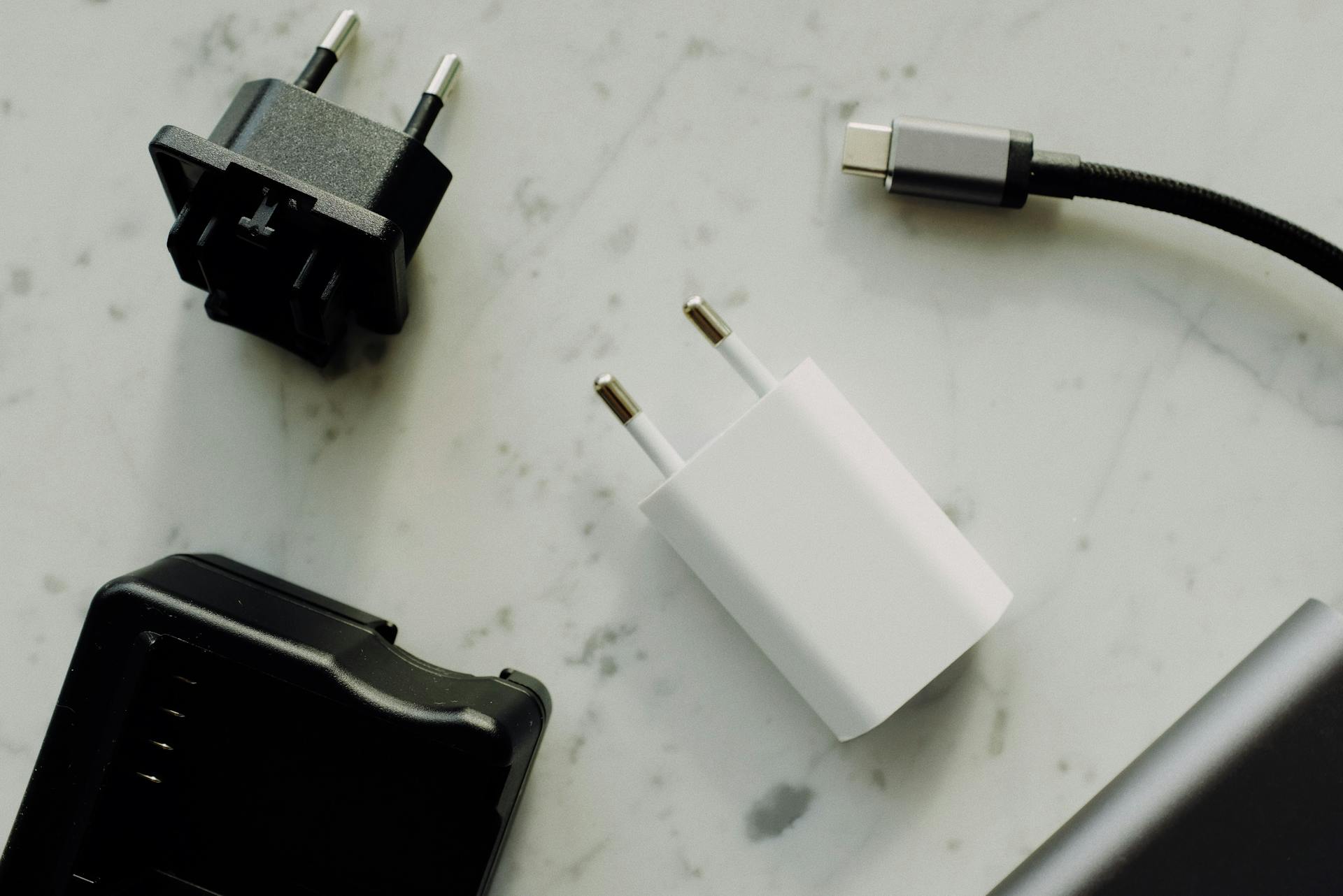 Collection of power adapters and a USB-C charging cable on a marble surface.