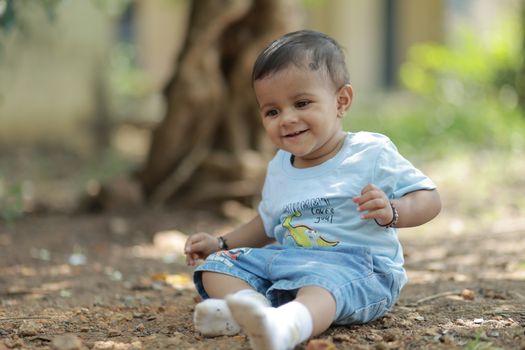 Cute baby sitting on the ground outdoors, enjoying a sunny day.