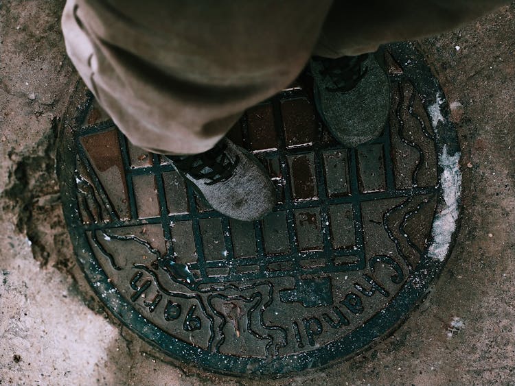 Crop Person Standing On Manhole Cover