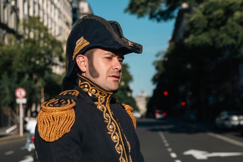 Free Adult male wearing elaborate historical military uniform standing proudly in a sunlit urban environment. Stock Photo