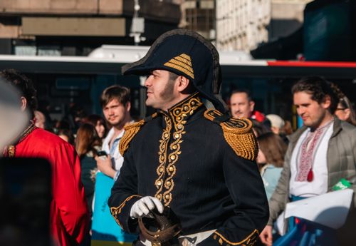 Free Man in historical military costume participates in a city parade with a lively crowd. Stock Photo