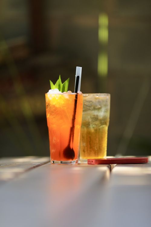 Free Two iced drinks with garnishes on a sunny outdoor table, perfect for summer refreshment. Stock Photo
