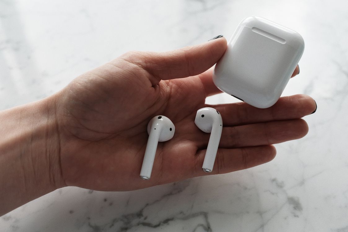Person holding an open white AirPods charging case in one hand