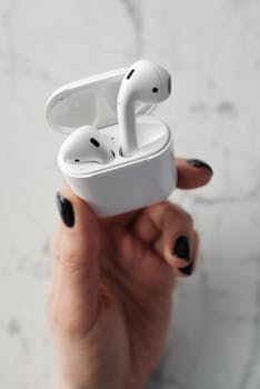 Close-up of sleek wireless earbuds in a hand, showcasing modern technology.