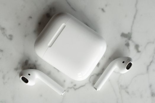 Close-up of wireless earbuds and case on marble, showcasing modern portable technology.