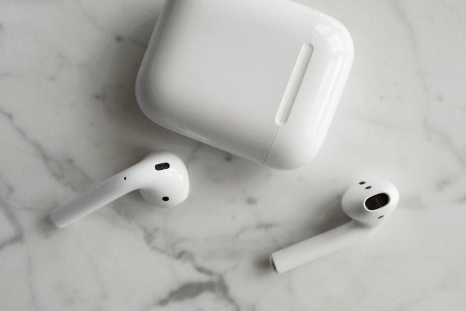 High-quality image of wireless earbuds and charging case on marble surface, showcasing modern technology.