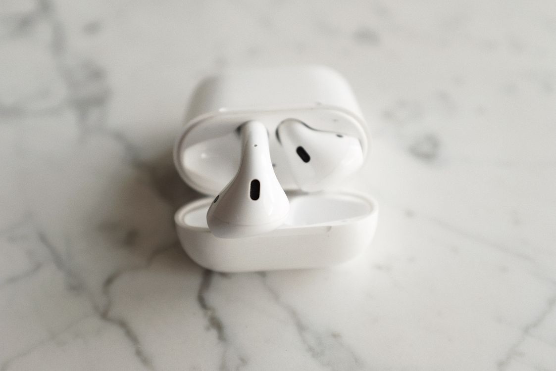 White wireless earbuds with charging case open on a marble background