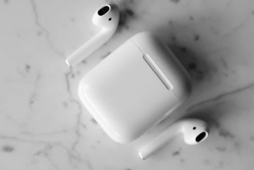 Close-up of wireless earbuds and charging case on a marble surface. Modern and sleek design.