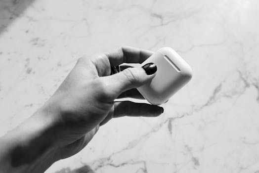 Artistic black and white photo of a hand holding a wireless earbud case.