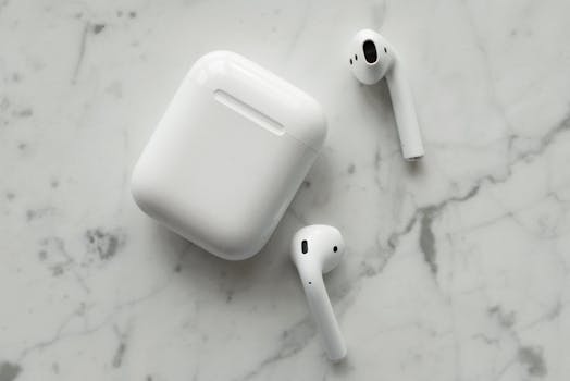 Close-up of wireless earphones and charging case on a marble surface, showcasing modern technology.