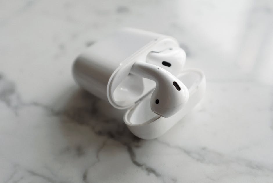 Close-up of wireless earbuds in an open charging case on a white marble surface.