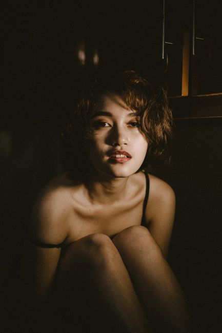 Moody portrait of a woman in dim light, capturing emotions and shadows.