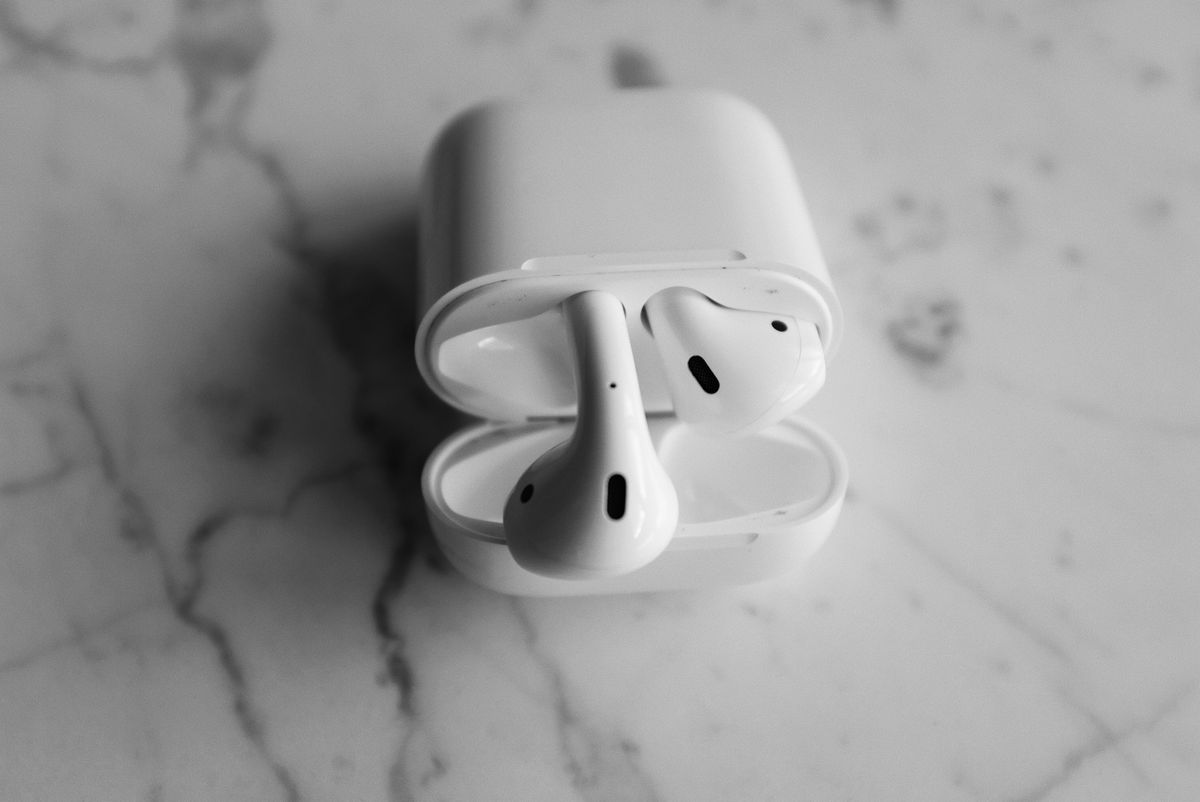 White open-fit wireless earbuds resting inside a charging case
