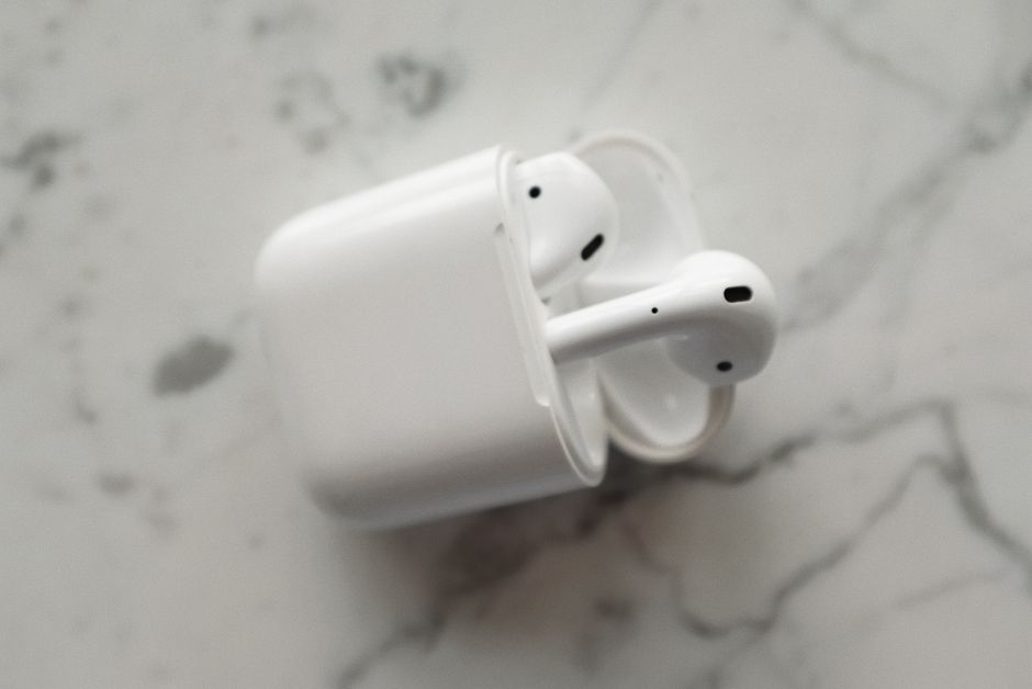 Modern wireless earphones in a sleek charging case on a marble surface.