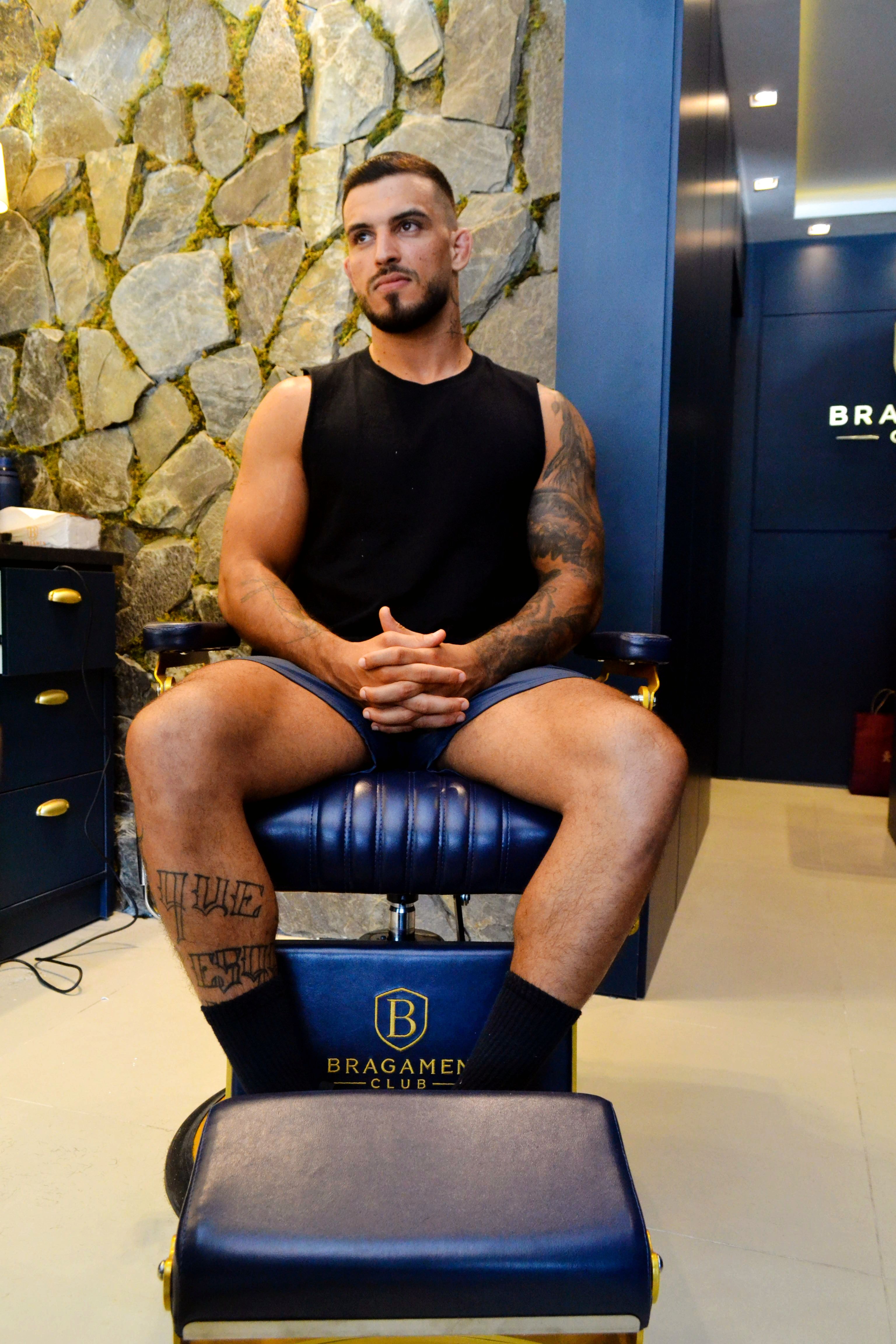 Man seated in a stylish barbershop chair, exuding confidence and style.