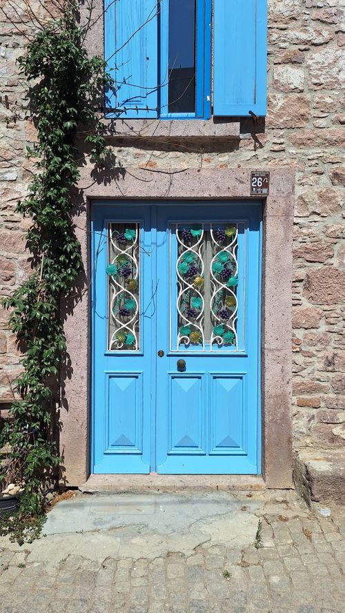 Free A picturesque blue door with stained glass details on a rustic stone facade in sunlight. Stock Photo