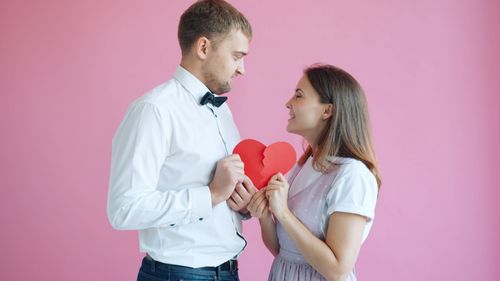 Free A couple holding a broken heart against a pink background, symbolizing relationship dynamics. Stock Photo