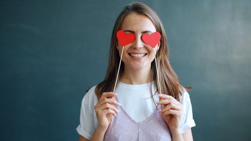 Free Smiling woman holding heart-shaped props over eyes, expressing joy and love. Stock Photo