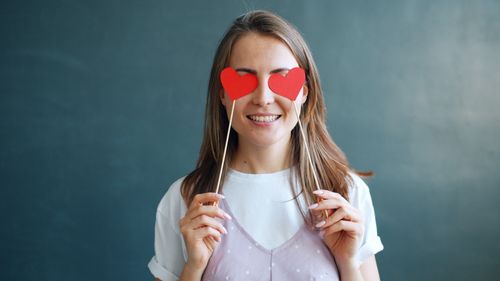 Free Happy woman with red heart props over eyes indoors. Perfect for Valentine's visuals. Stock Photo