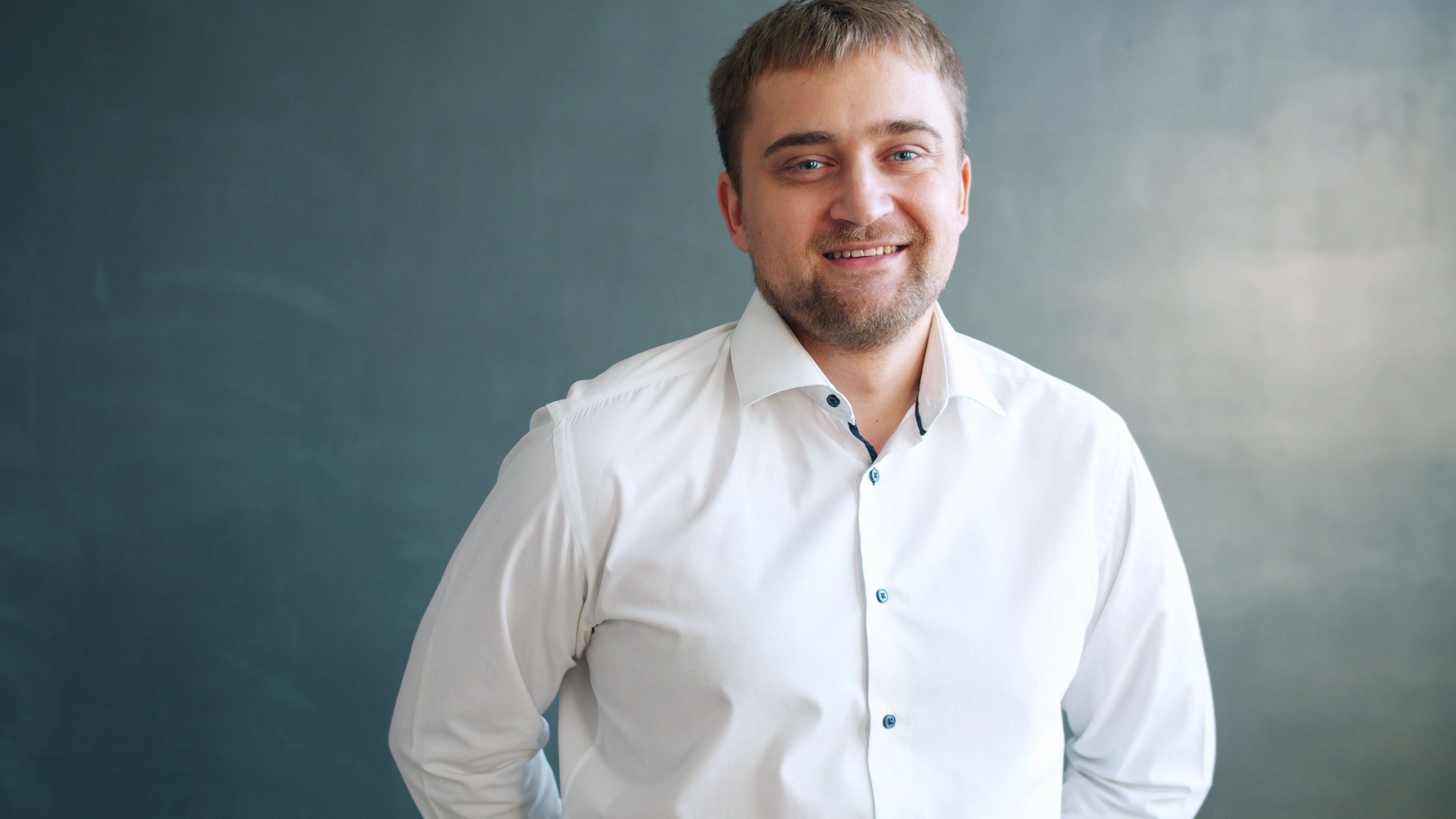 Portrait of a smiling man in a white shirt against a blue background. Ideal for business or lifestyle content.