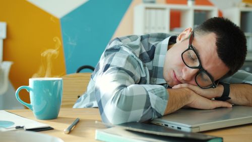 Free Tired man sleeping on laptop with coffee, showcasing workplace fatigue. Stock Photo